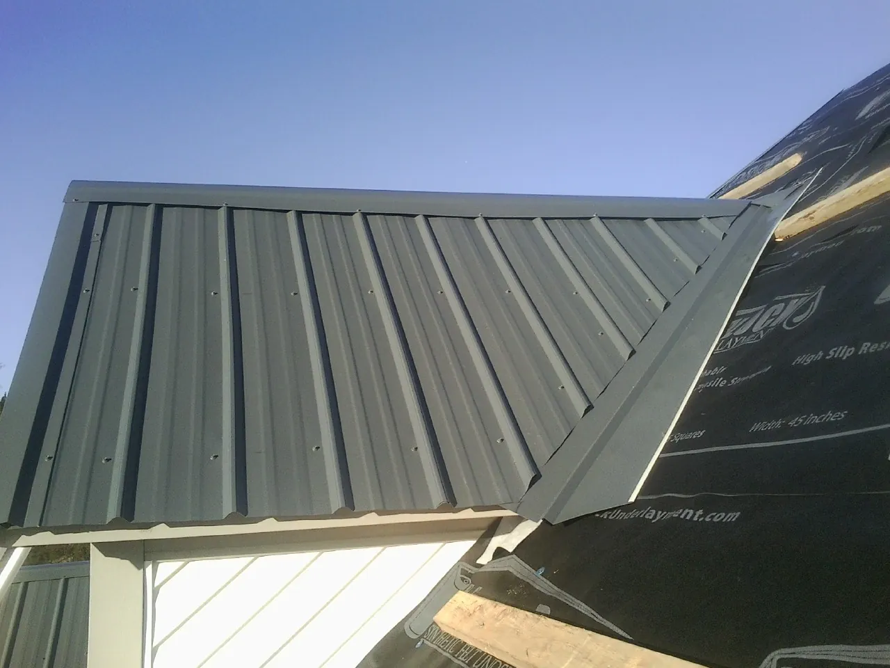 Gray metal roof panels going on over a garage gable in Cogswell