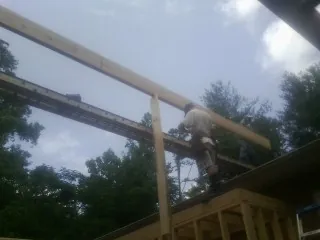 Carpenter setting a ridge beam over a new addition frame — Ice Dam Removal by Roofing Brothers in Cogswell