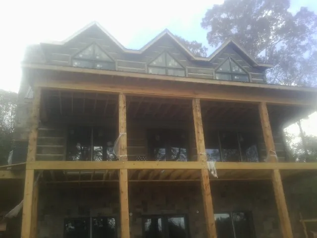 Dormers and porch framing on a large log home under construction — Roof Coating work by our crew in Cogswell
