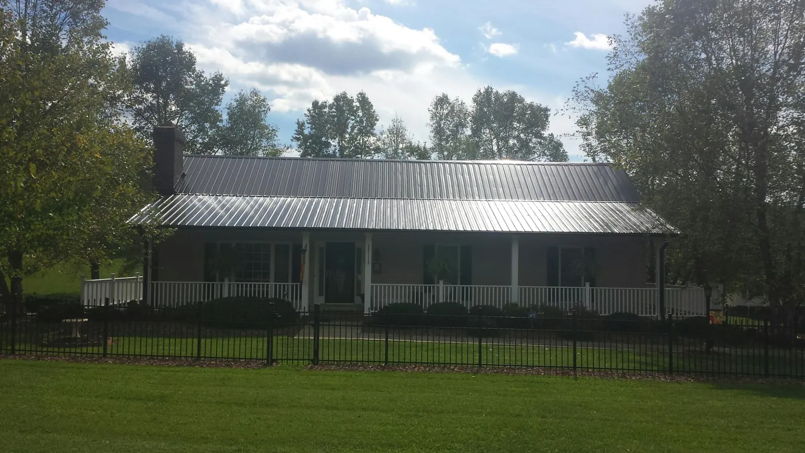 Gray metal roof on a brick ranch with a full width front porch — Gutter Guard Installation work by our crew in Cogswell