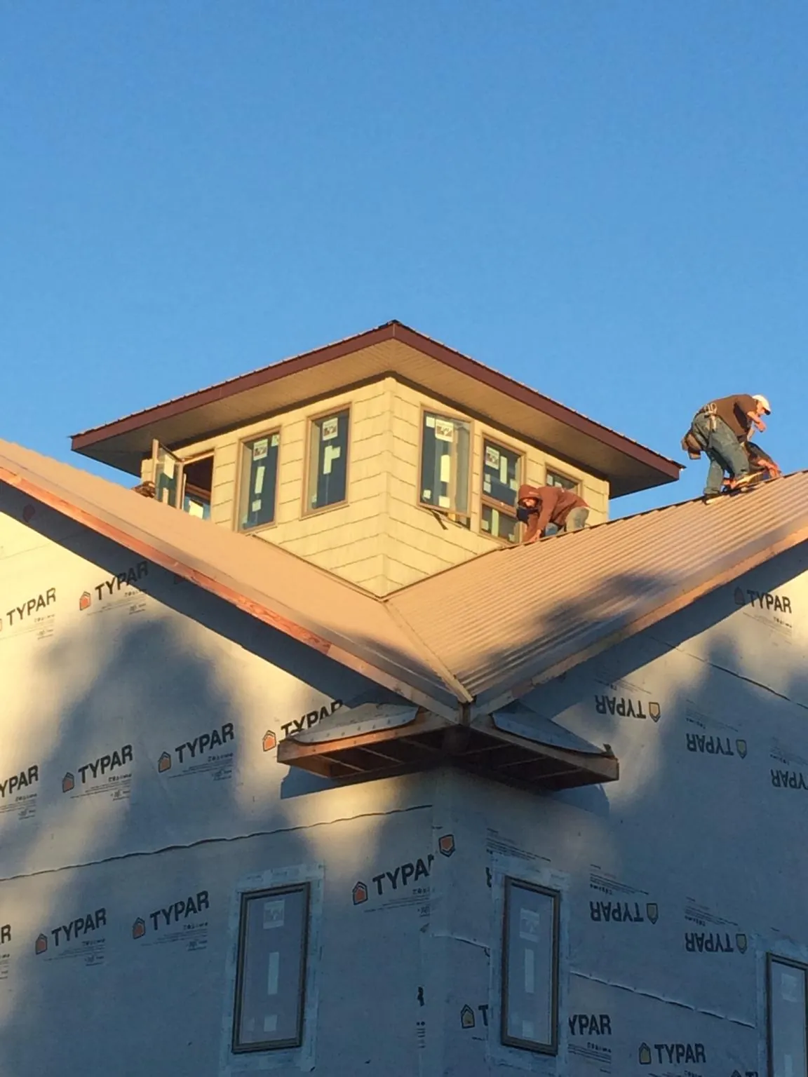 Roofers working around a rooftop cupola on a new metal roof at sunset — Roof Waterproofing in Cogswell by Roofing Brothers